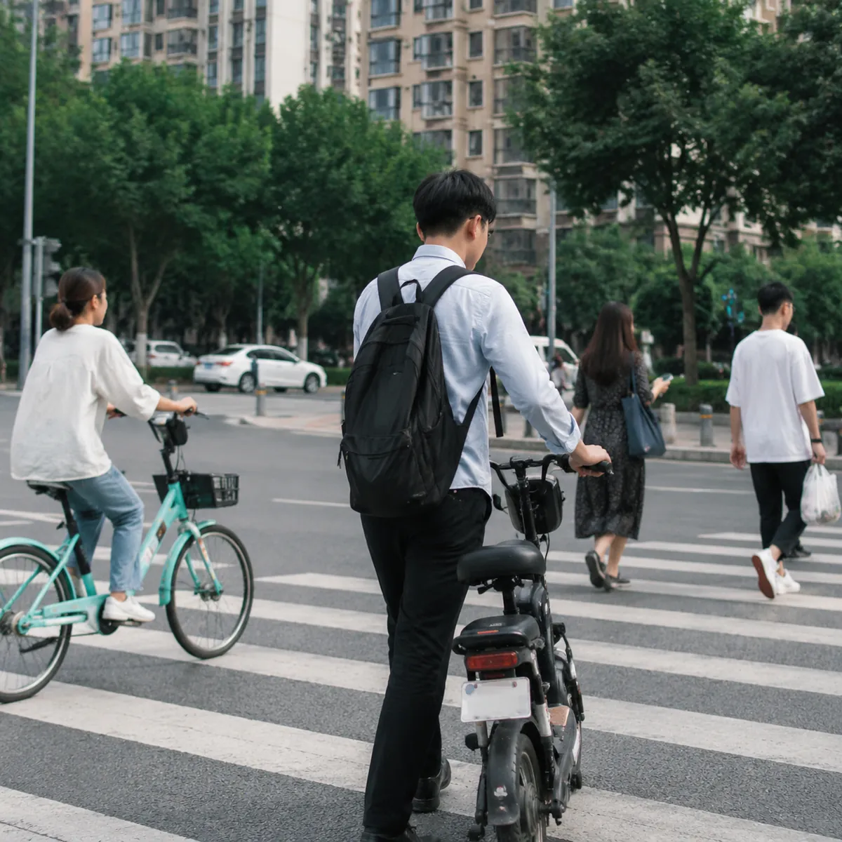 成都上班族通勤推电动车过马路